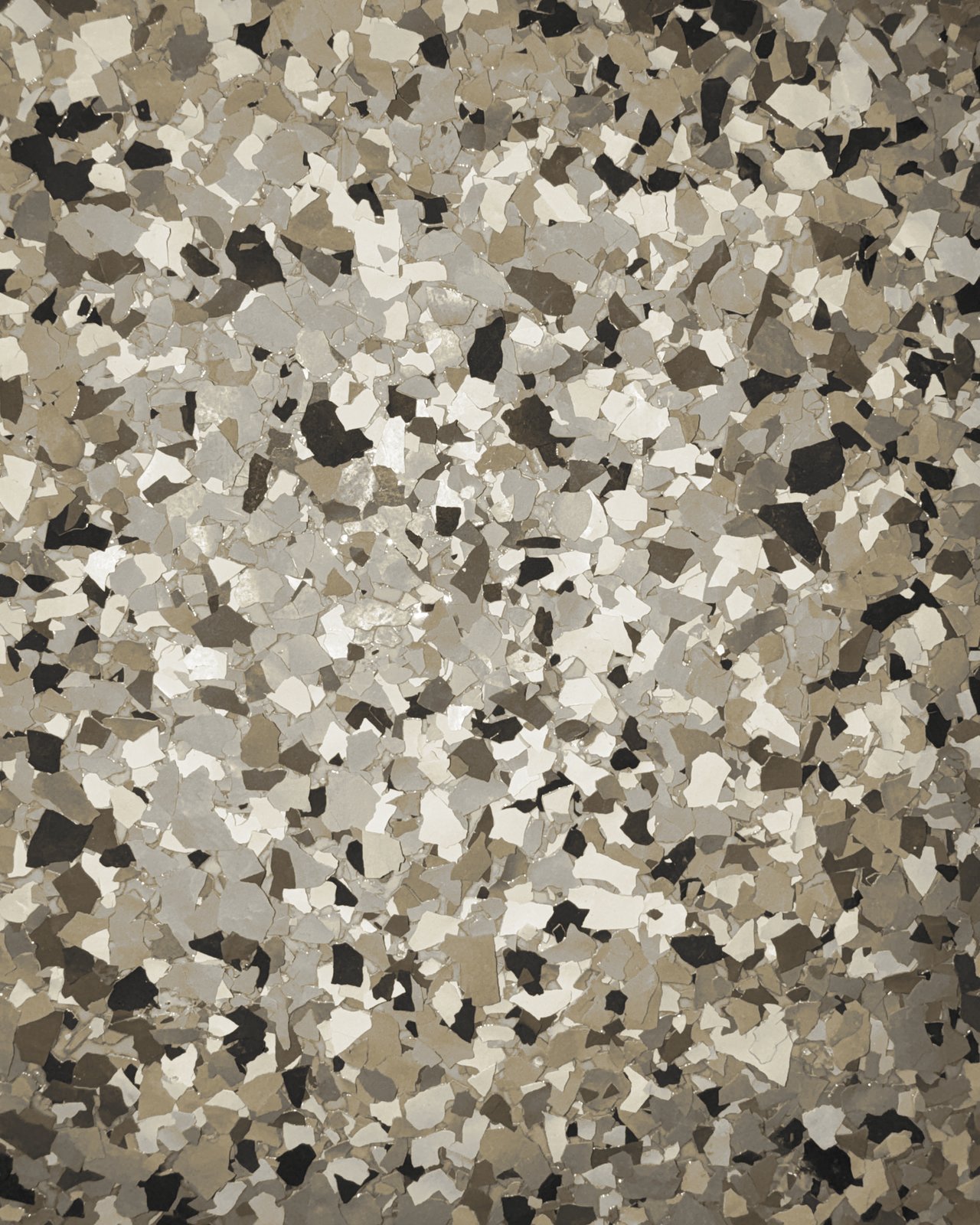 Close-up of a tan, cream, brown, and black full-flake epoxy floor finish