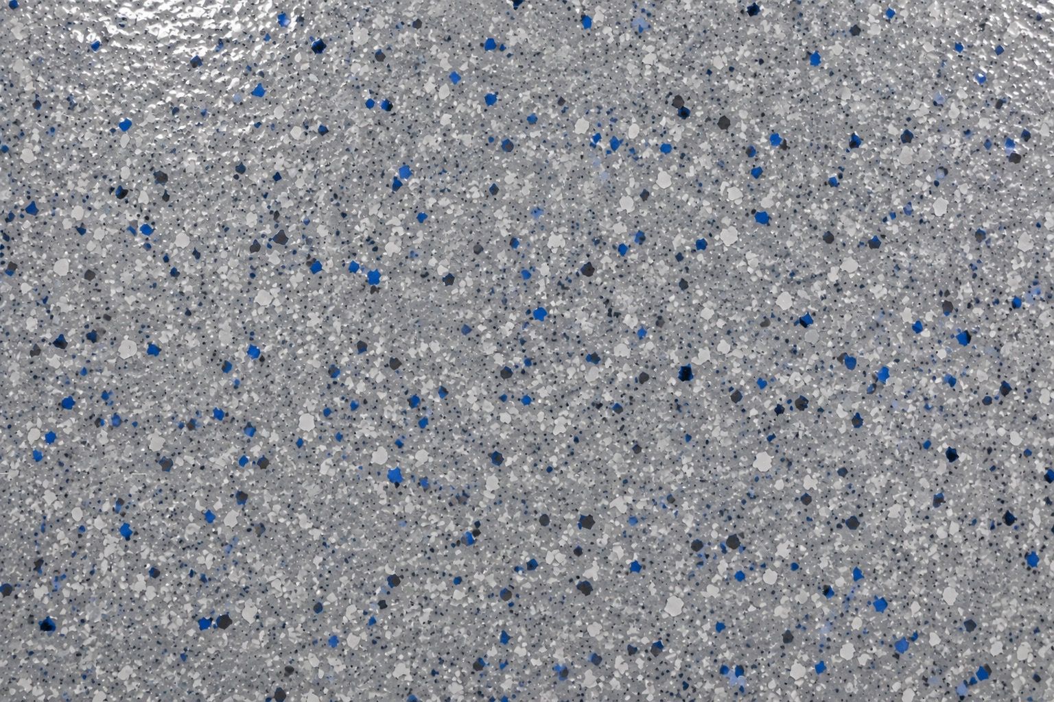 Close-up of a blue, white, and black flake-broadcast epoxy floor finish