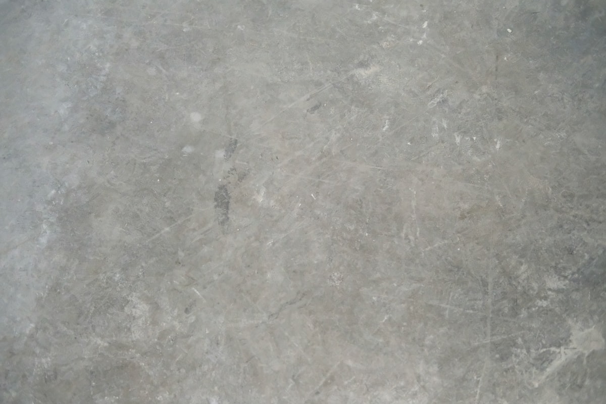 Bare gray concrete garage floor with light scuffs before coating